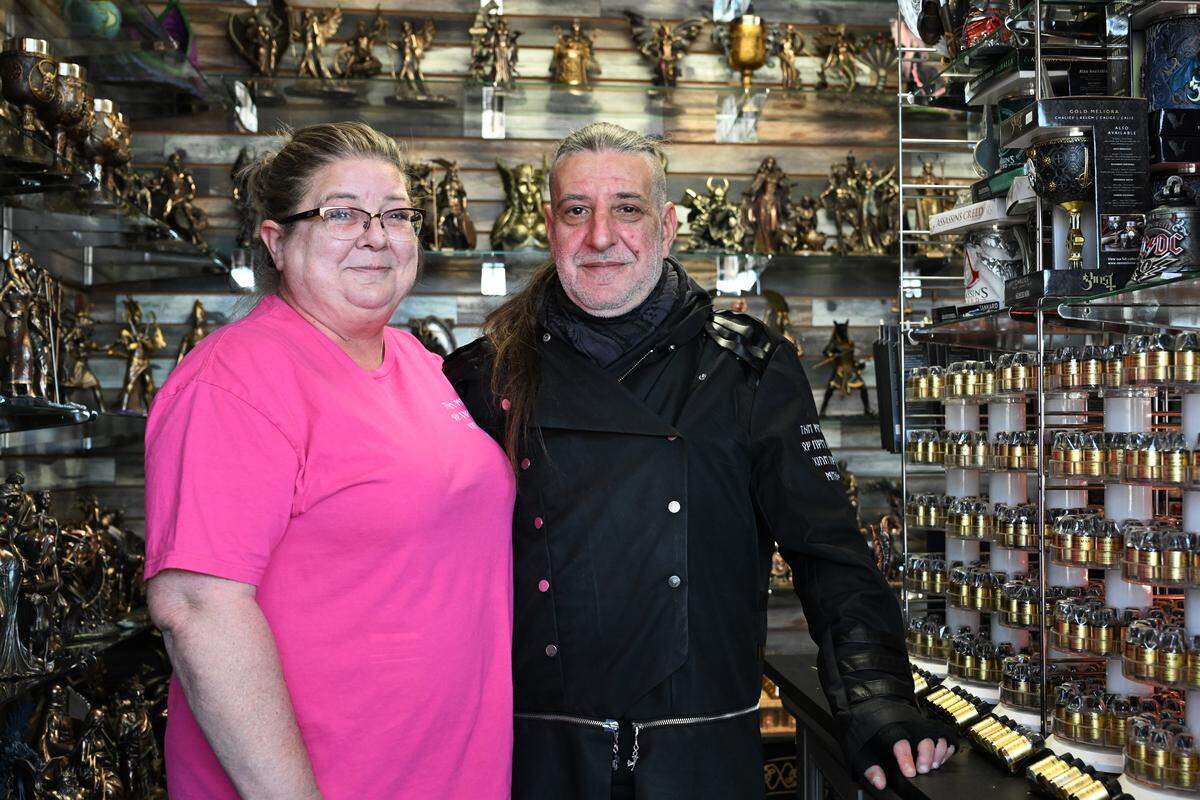 The M Cave owners Robin (left) and Stefanos Lianos pose between merchandise inside their fantasy gift shop in Centerville.