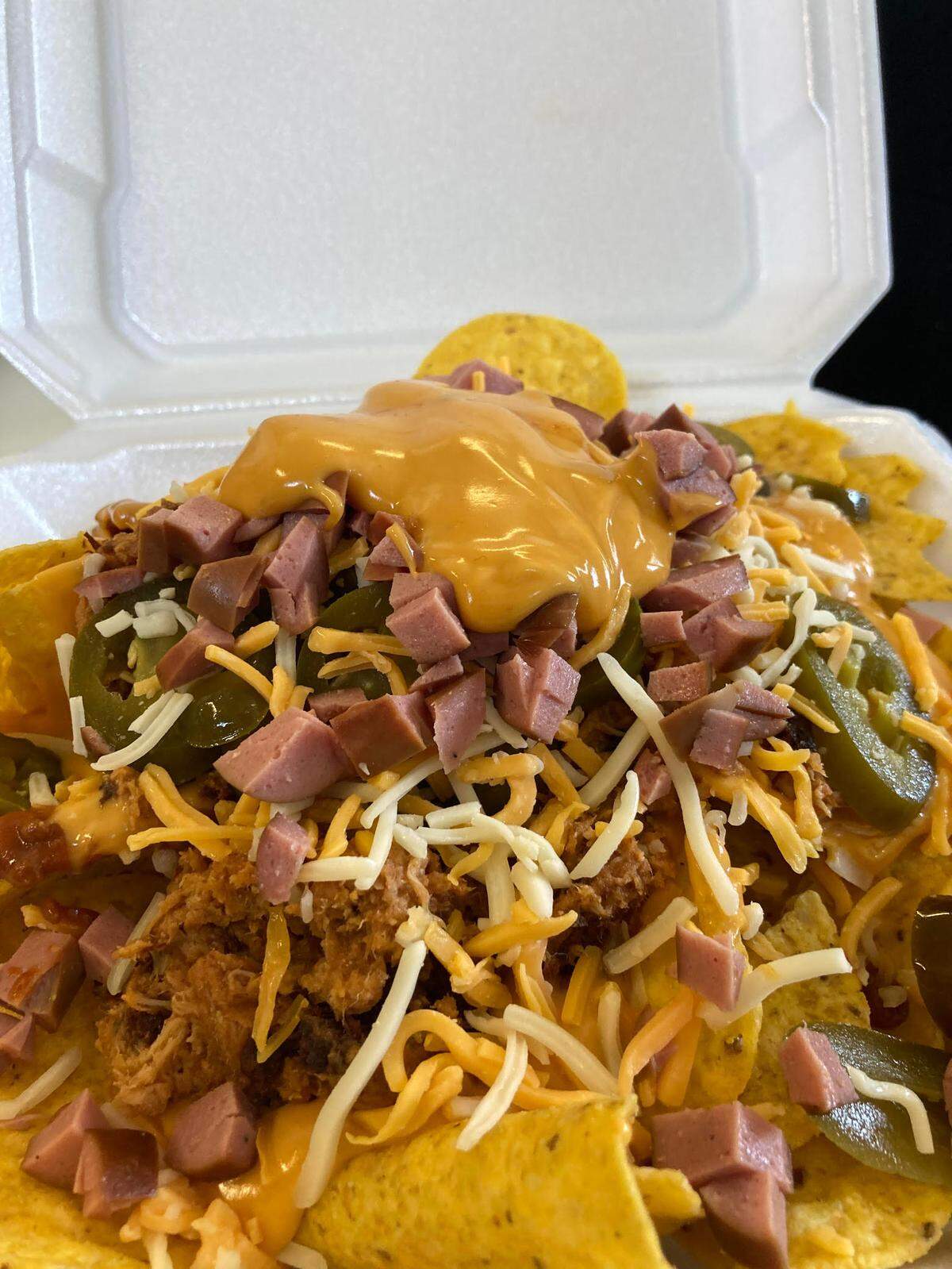 Disaster nachos from Doggie Dogs. Disaster nachos are a plateful of nacho chips with chili sauce, nacho cheese, barbecue chicken, jalapenos, shredded cheese, cut-up hot dogs and then some more nacho cheese on top.