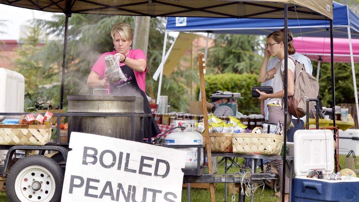 Keisha Fuller of Bolingbroke dishes out a bag of boiled peanuts during The Mill Market Expo on Saturday in Forsyth.