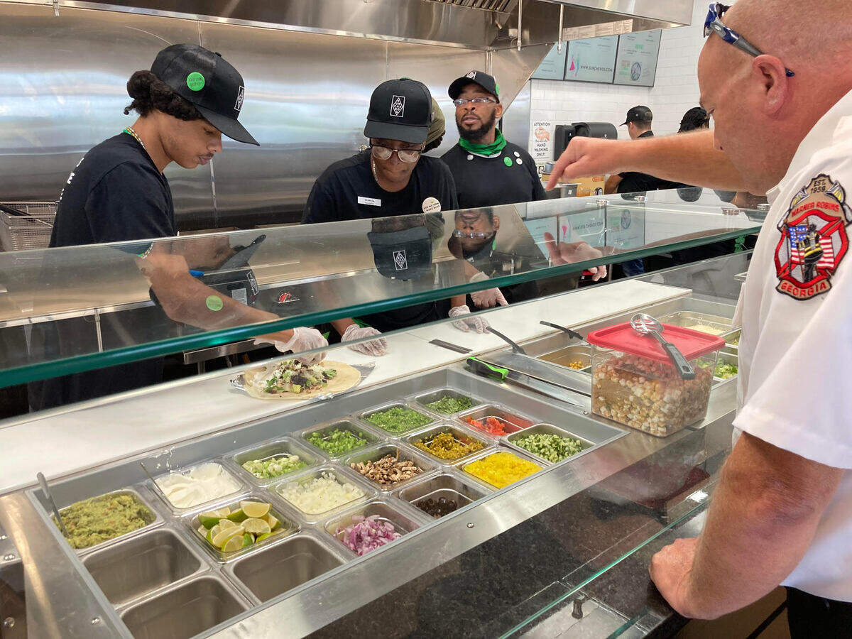 Warner Robins fire Capt. Kevin Kendrick selects toppings for a burrito at Surcheros Fresh Mex restaurant in Warner Robins at a friends and family event in August 2024, the day before the grand opening.