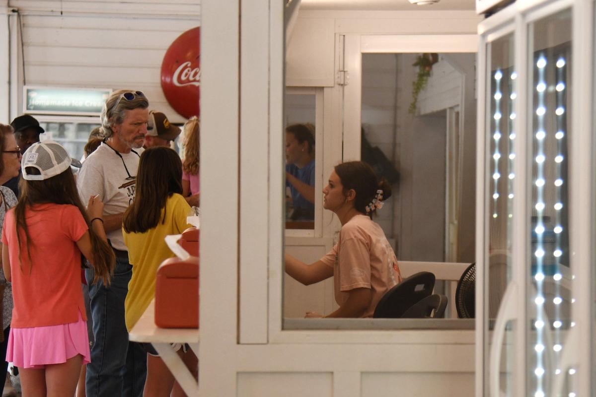 A Dickey Farms employee brings an order of soft serve to shop patrons on Wednesday, July 3, 2024, in Musella, Georgia. Dickey Farms is the oldest, continuously operating peach packinghouse in Georgia and offers tours and sells homemade goods and produce in their shop.