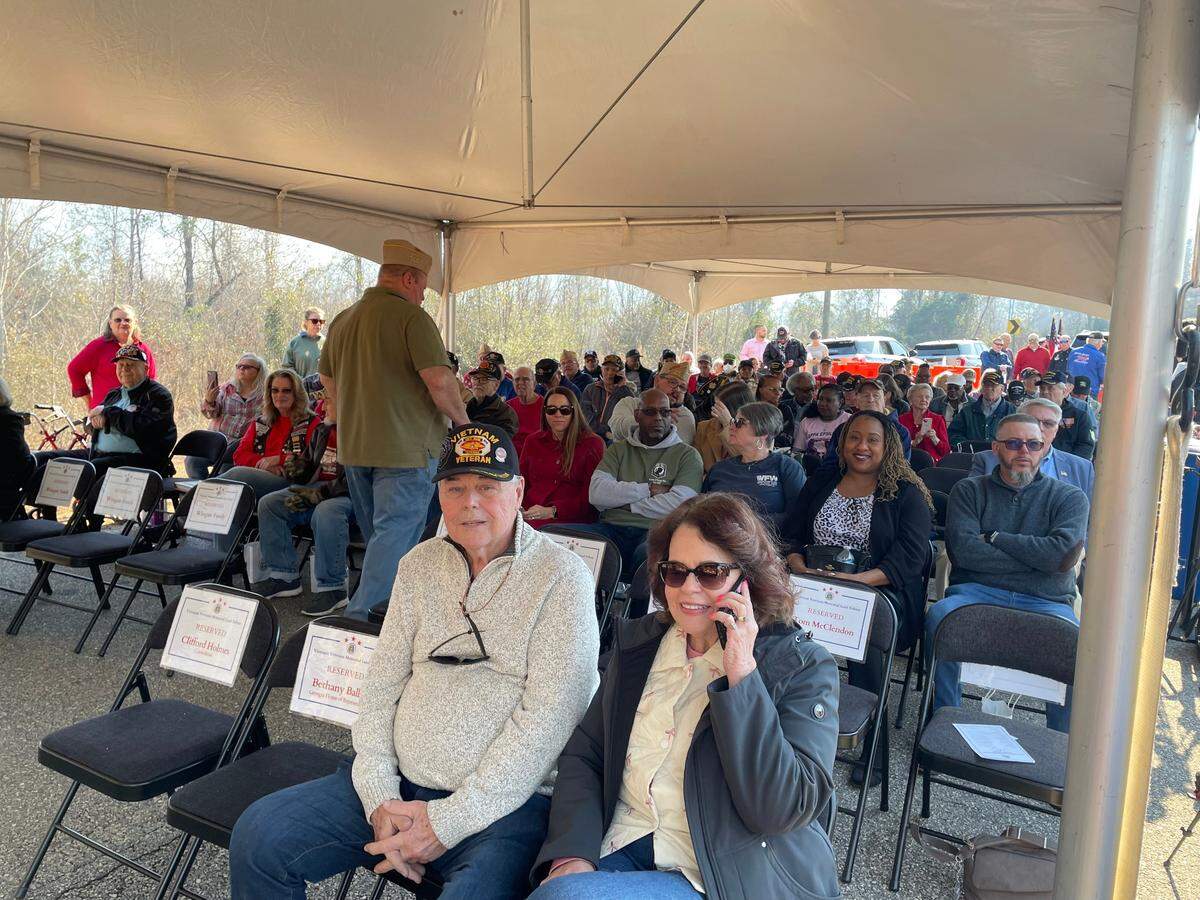 Vietnam veteran Mike Driggers (black ball cap/front row), who donated the land for the future home of a Vietnam Veterans Memorial in Warner Robins, waits as people arrive for a land tribute Friday. He received a standing ovation at the event for donating the property to the city of Warner Robins.