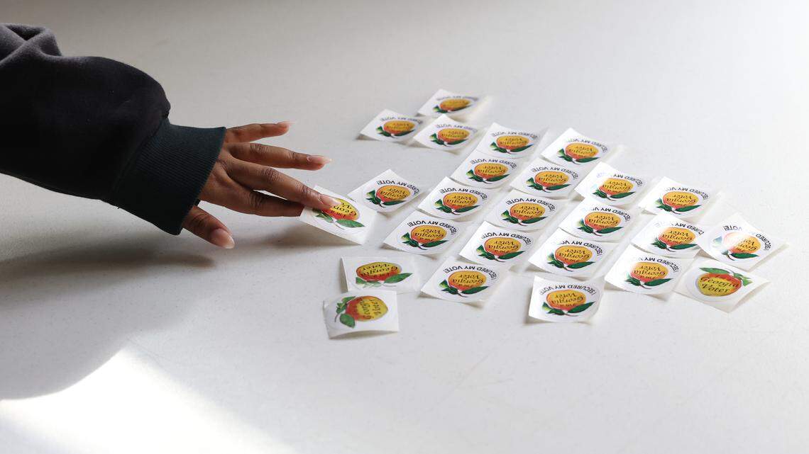 Amaana Hinds reaches for a sticker after voting on Election Day on Tuesday, Nov. 5, 2024, at the Lake Wildwood Clubhouse polling location in Macon, Georgia.