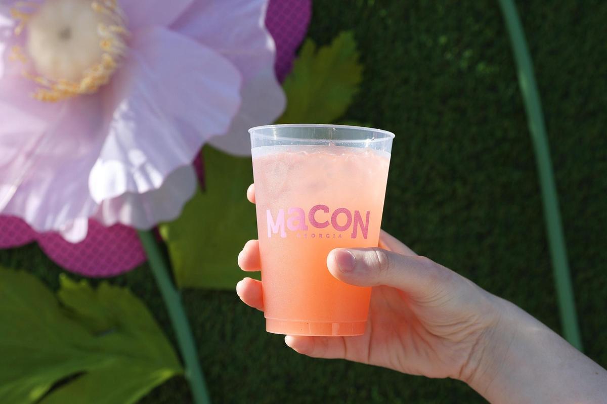 A Hibiscus Lychee Flower Sour Cocktail from Kinjo Kitchen and Cocktails sits in front of a floral background at the Pink Provisions Trail preview on Friday, March 21, 2025, in downtown Macon, Georgia. Local Macon restaurants and bars debuted pink and cherry-inspired bites and drinks to celebrate the International Cherry Blossom Festival, all of which are available throughout the festival.