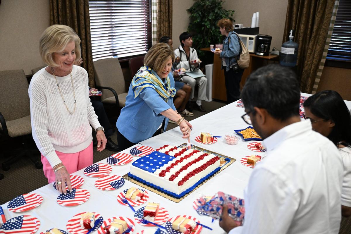 Macon Town Committee of the National Society of the Colonial Dames of America in the State of Georgia vice chair Isabelle Sullivan (left) and chair Lucia Strickland serve American flag cake to newly naturalized citizens and their families after the conclusion of the naturalization ceremony at the United States District Court Middle District of Georgia on Wednesday, April 9, 2025, in Macon, Georgia. The 22 foreign nationals that petitioned for American citizenship represented 15 countries of origin in the annual ceremony that takes place every spring in Macon.
