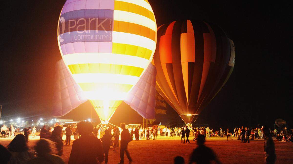GRANT BLANKENSHIP/THE TELEGRAPHPeople admire the glow of hot air ballons against the night sky at a previous year’s installment of Tunes and Balloons.