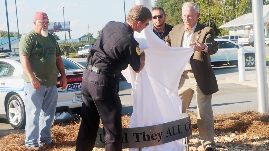 Warner Robins Police Chief Brett Evans and Jim Sehorn, a former prisoner of war in Vietnam, unveil a monument at the police department flag pole in remembrance of prisoners of war and those who remain missing in action.