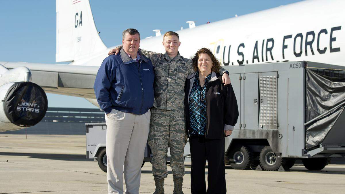 Airman 1st Class Mike Horne stands with his mother, Lorilee Cuvillier, and father, Chris Horne, in front of an E-8C J-STARS plane at Robins Air Force Base.