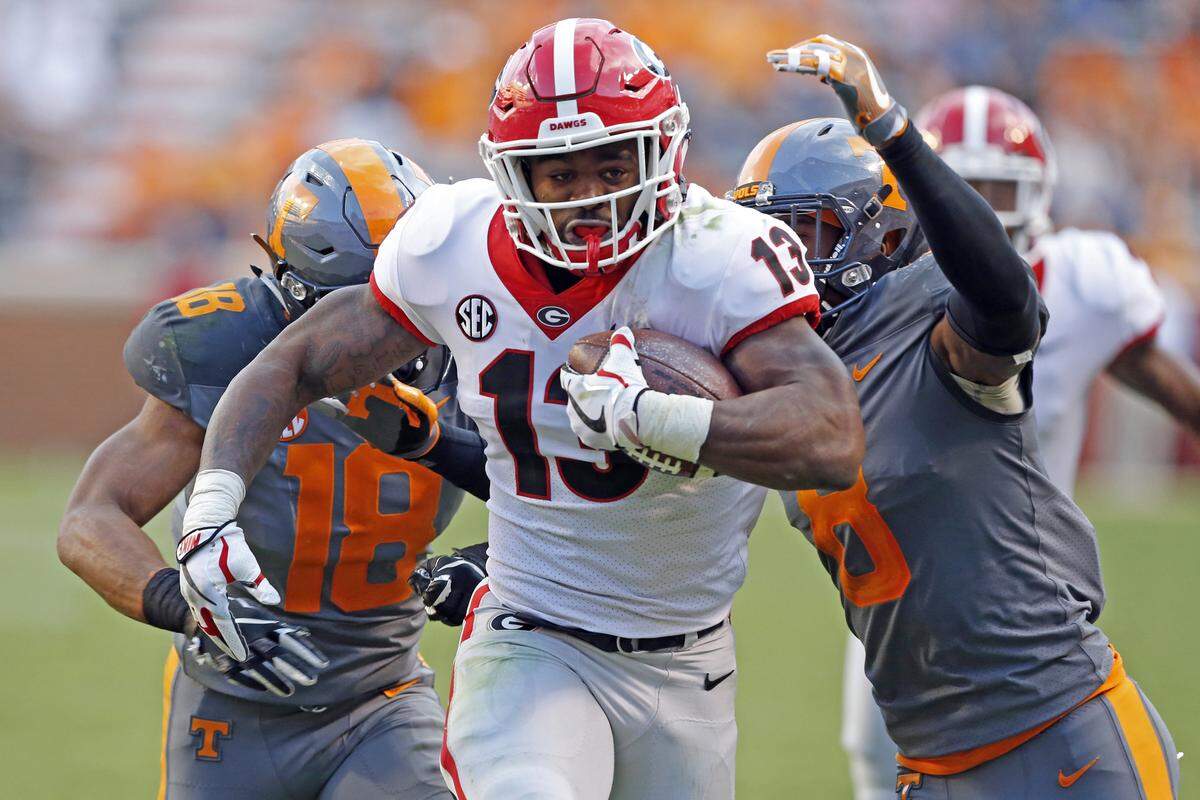 Georgia running back Elijah Holyfield (13) outruns Tennessee defensive back Justin Martin (8) and defensive back Nigel Warrior (18) in the second half of an NCAA college football game Saturday, Sept. 30, 2017, in Knoxville, Tenn. Georgia won 41-0.