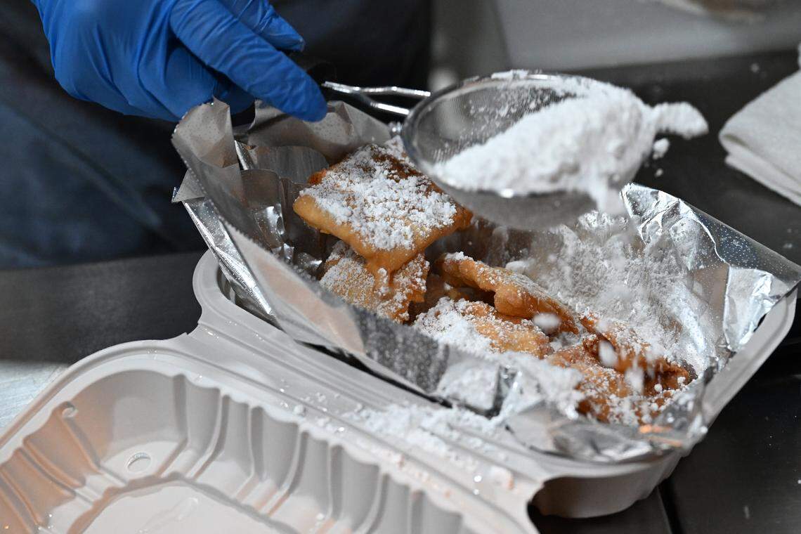Tammy Simmons adds powdered sugar to an order of beignets, a specialty item for the new Little Light Coffee Co. drive-thru off Ga. 247. Simmons also makes the mini doughnuts.