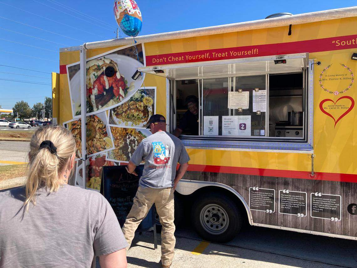 People line up at the ABC Catering LLC food truck outside Advance Auto Parts off Ga. 96 in Warner Robins.