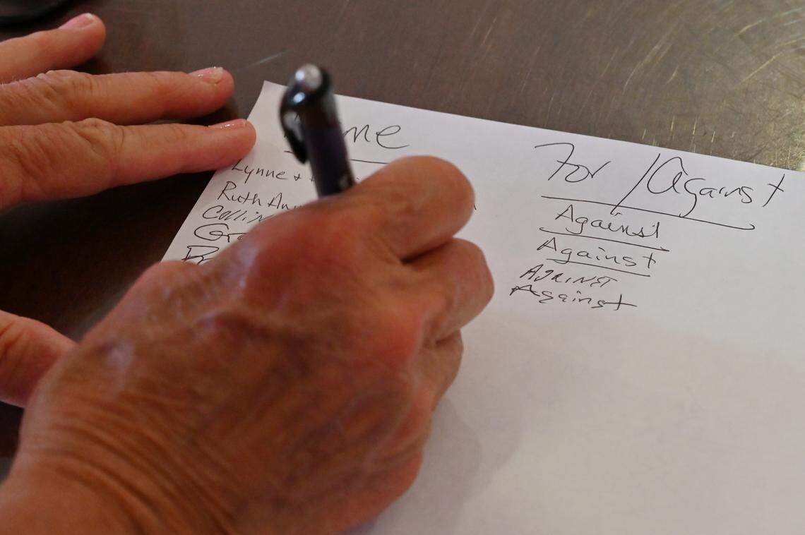 A Monroe County Planning and Zoning Board meeting attendee signs in, as other people have written “against,” in opposition of a proposed rezoning for a new data center in Bolingbroke at the Monroe County Conference Center on Monday, July 28, 2025, in Forsyth, Georgia. The Monroe County Planning & Zoning Board voted unanimously Monday evening against rezoning about 90 acres of land for the project. 