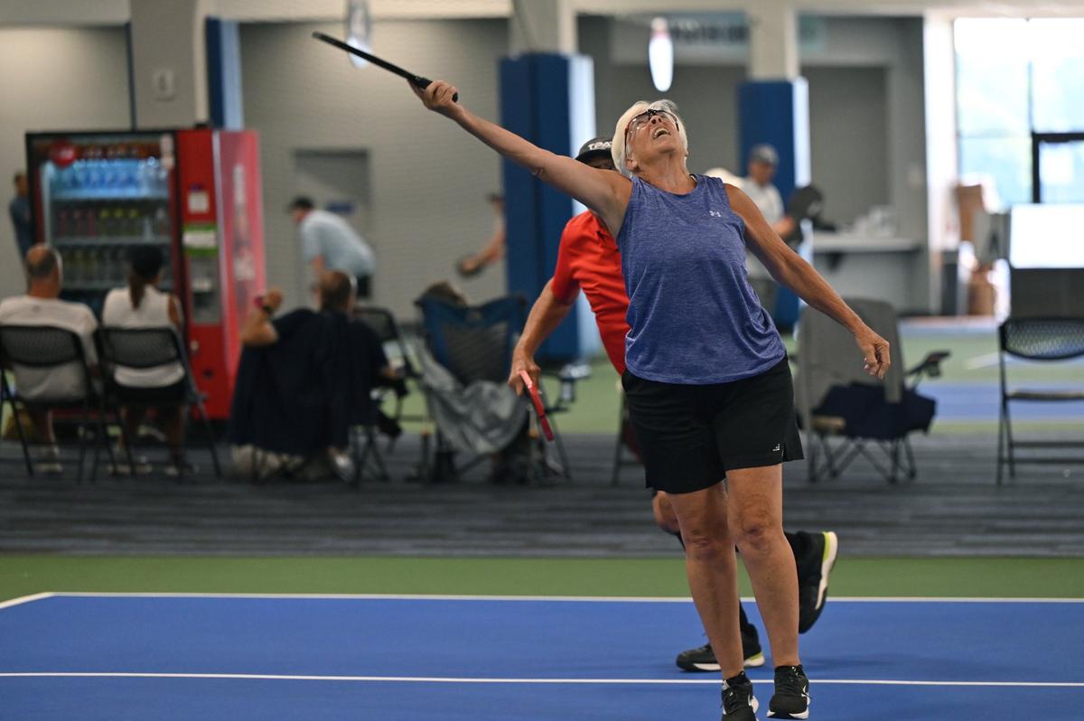 Betsey Lieberman, 72, from Tallahassee, Florida, reaches for the ball during a mixed doubles match on the second day of the United States Senior Pickleball Indoor National Championships on Saturday, July 13, 2024, at Rhythm and Rally Sports & Events in Macon, Georgia. United States Senior Pickleball hosted its inaugural indoor national championships this year, spanning three days and bringing hundreds of seniors to compete in Macon from across the country.