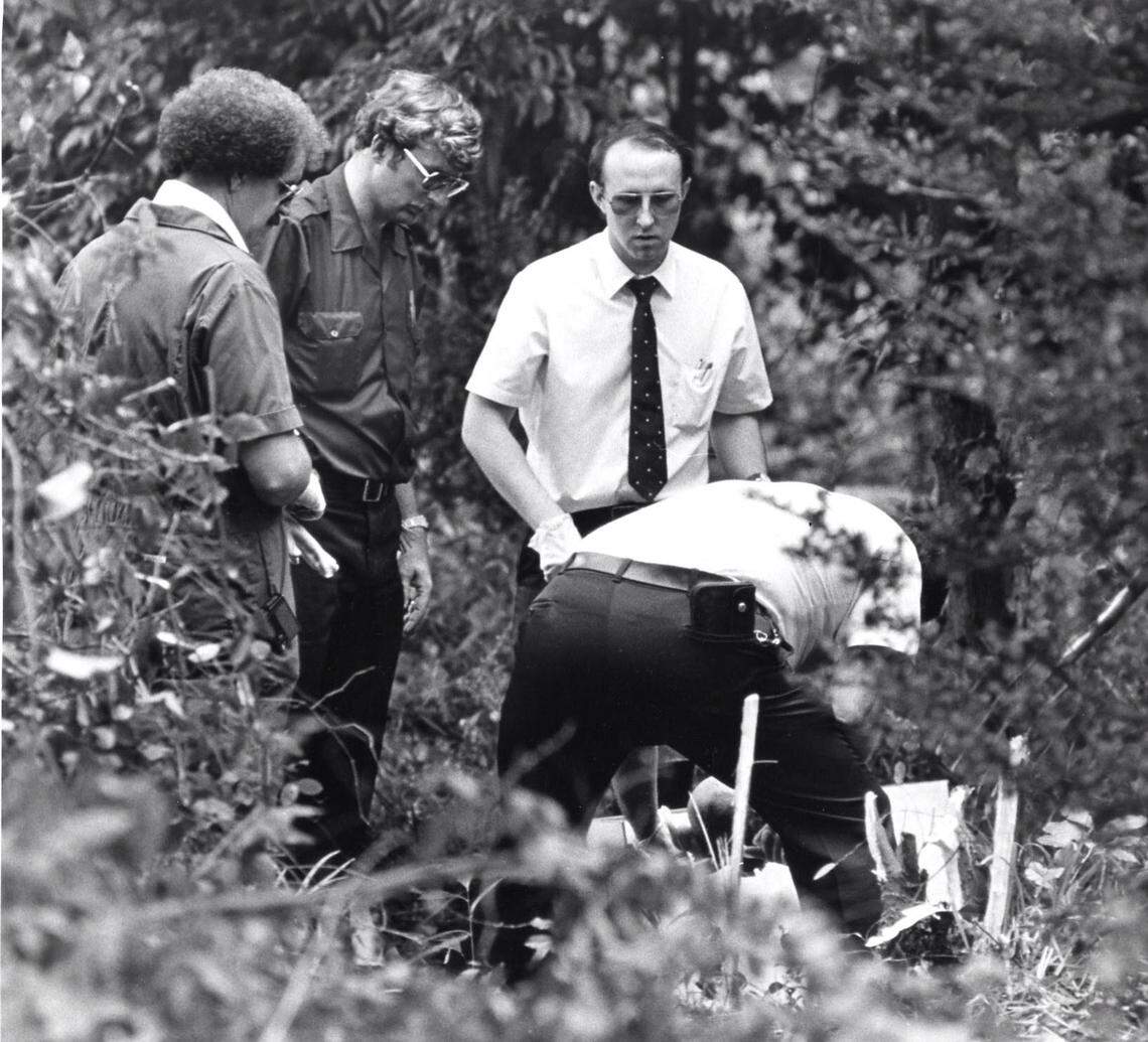 Medical examiner Dr. Byron Dawson, right, examines human remains discovered near Washington Park in August 1982. Macon police officers Bobby Lowe, left, Donny Foster, center, and GBI crime scene investigator Jay Jarvis, right, look on.