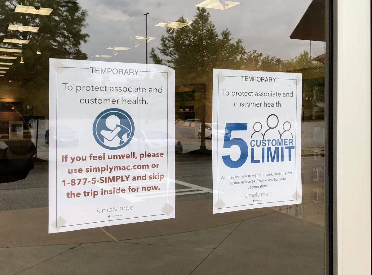 Signs on the door at Simply Mac in the Shoppes at River Crossing.