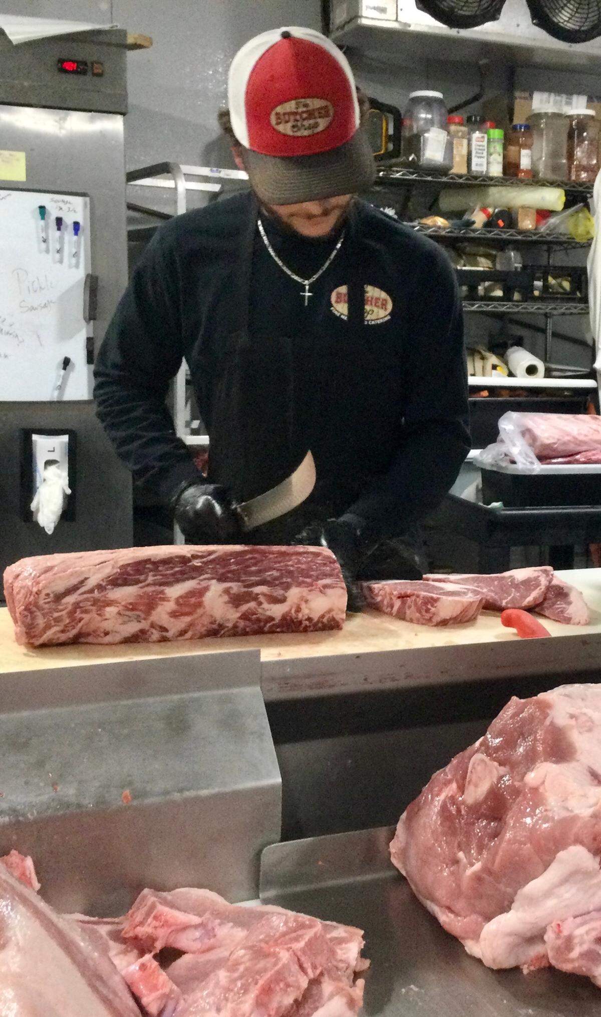 Jake Spillers, butcher in training at the popular speciality market, The Butcher Shop, in Warner Robins, slices up some ribeye steak. Spillers will be one of the butchers helping to open a second location of The Butcher Shop in Macon.
