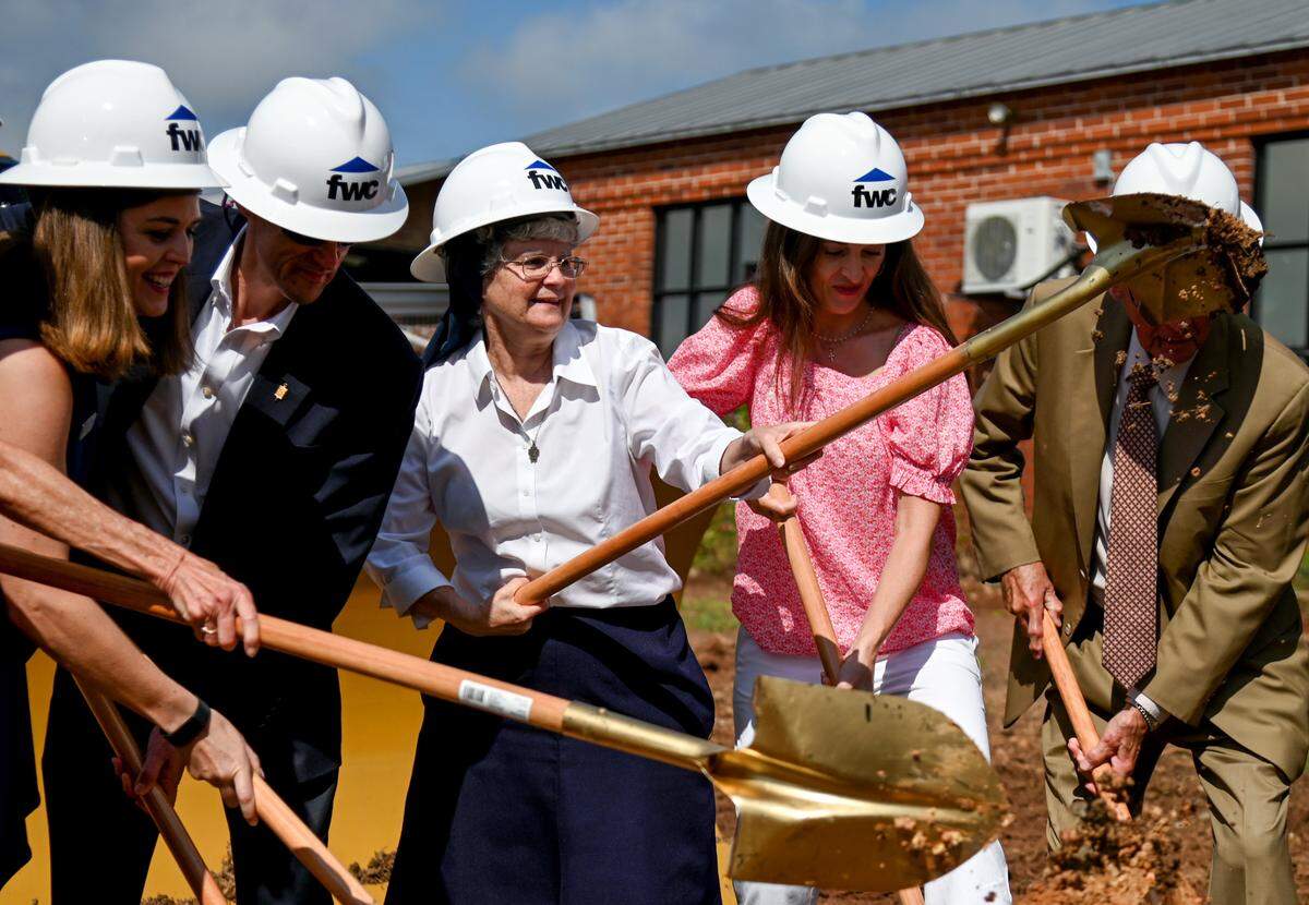 Sister Theresa Sullivan, center, director of Daybreak Day Resource Center, tosses a shovel of dirt Thursday morning during a groundbreaking ceremony of the future Central City Apartments and Daybreak Respite and Health Clinic.