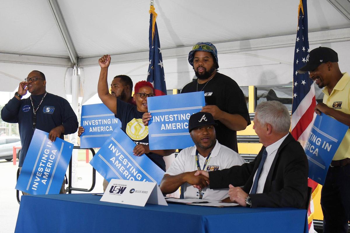 Blue Bird voluntary organizing committee member Patrick Watkins (left) shakes hands with Blue Bird CEO Phil Horlock after signing the Blue Bird union contract on Friday, July 19, 2024, at the Blue Bird manufacturing plant in Fort Valley, Georgia. Blue Bird electric bus manufacturing workers ratified their first union contract in May, joining United Steelworkers and securing wage increases, safety improvements and more employee benefits.