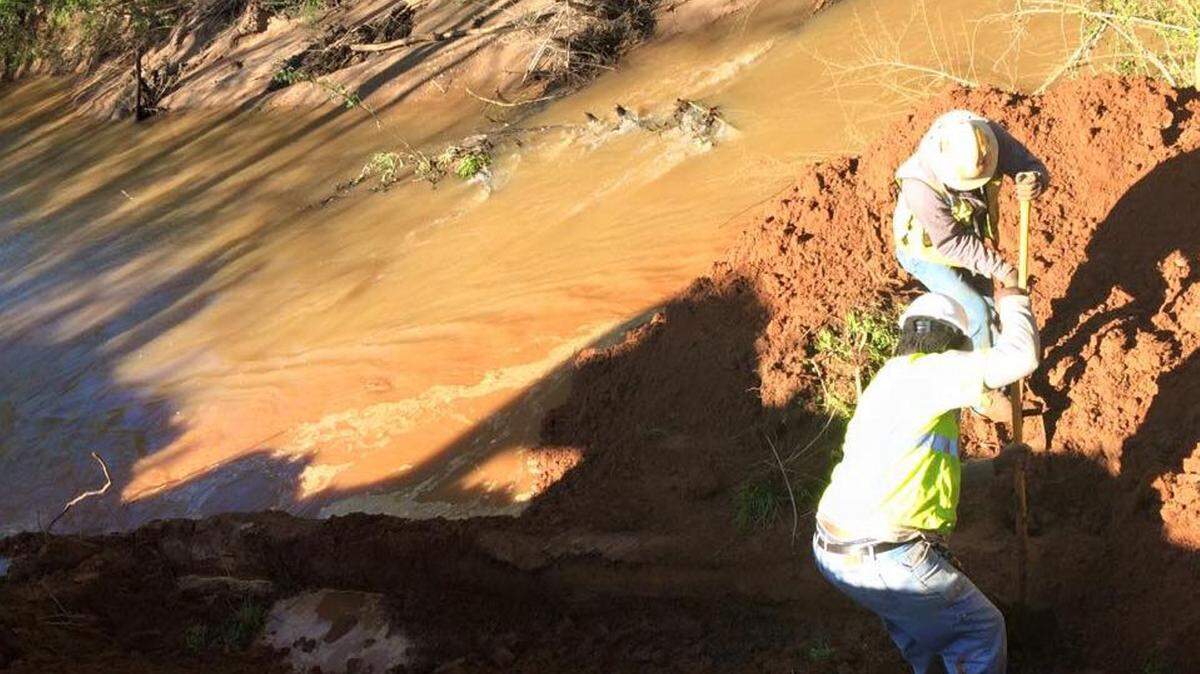 Workers dig around a water pipe that ruptured, threatening to leave the city without water Sunday afternoon.