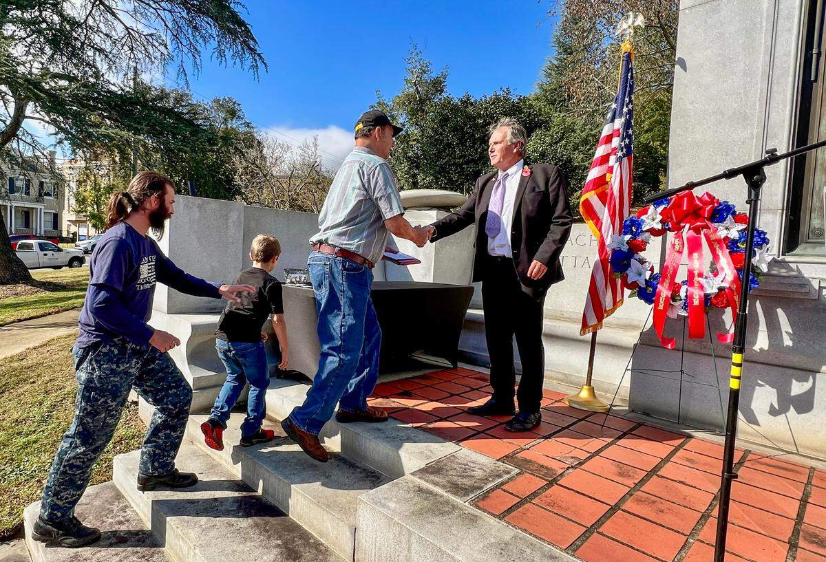 Middle Georgia State president Christopher Blake shakes hands with veterans while handing out challenge coins during a Veterans Day ceremony at Coleman Hill Thursday. The event was held at the World War I monument honoring members of the 151st Machine Gun Battalion, 42nd Rainbow Division.