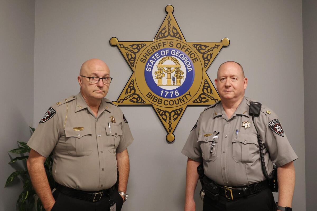 Maj. Robert Spires of the Bibb County Sheriff’s Office’s communications division (left) and Maj. Eric Walker of its patrol division pose in the sheriff’s office on Wednesday, April 2, 2025, in Macon, Georgia. Deputies’ swiftness to respond to an incident largely depends on whether 911 callers disclose if someone is injured or not, officials explained.