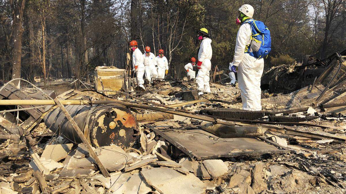 Volunteer members of an El Dorado County search and rescue team search the ruins of a home Nov. 18, looking for human remains, in Paradise, Calif., following a wildfire.