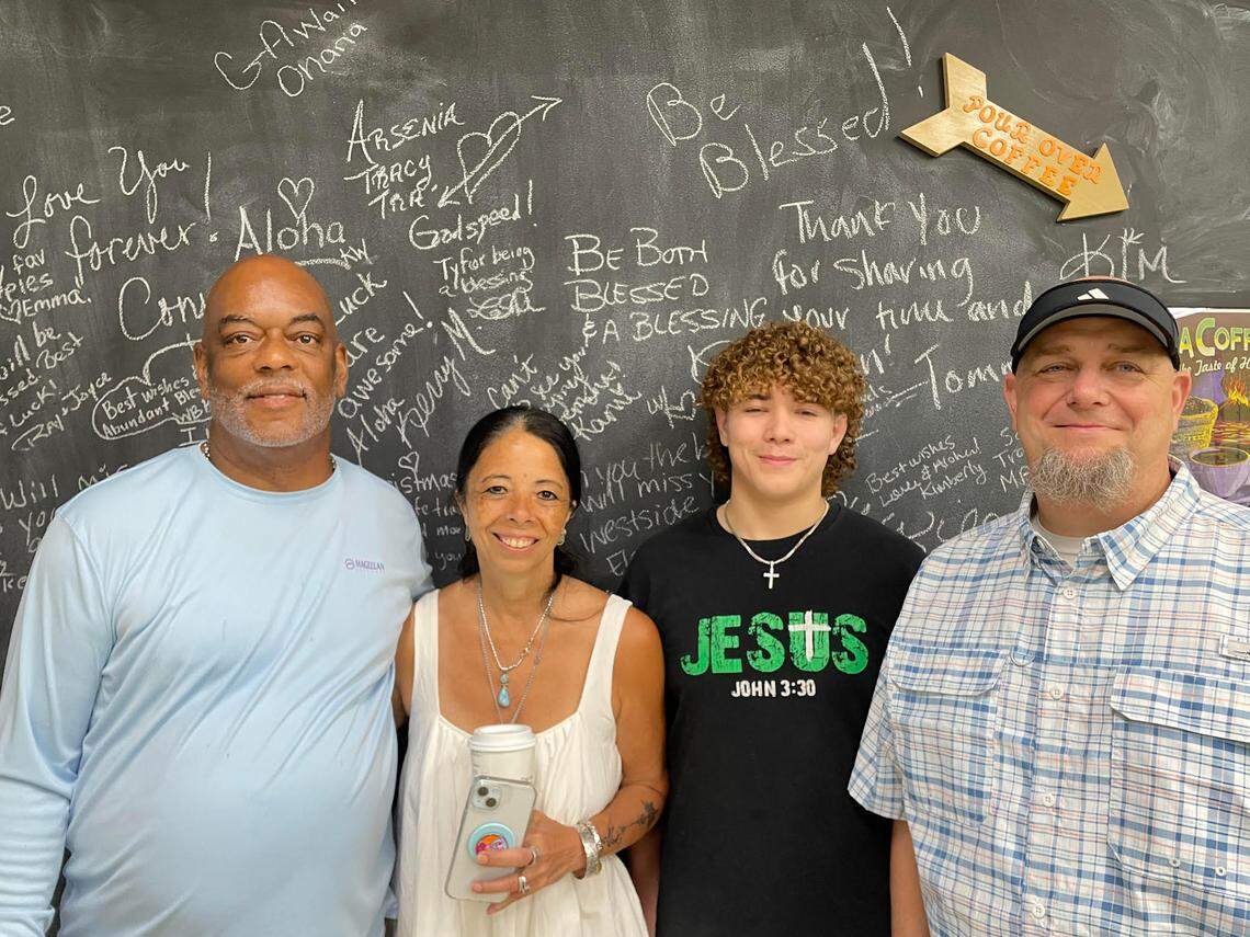 Keith and Roz Turner, original owners of The Apple Basket, with new co-owner Clayton Brown and his 20-year-old son, Eli Brown, who is helping out over the summer at the shop’s reopening Monday, May 5, 2025. The photo is taken in front of chalk board where customers can leave comments.