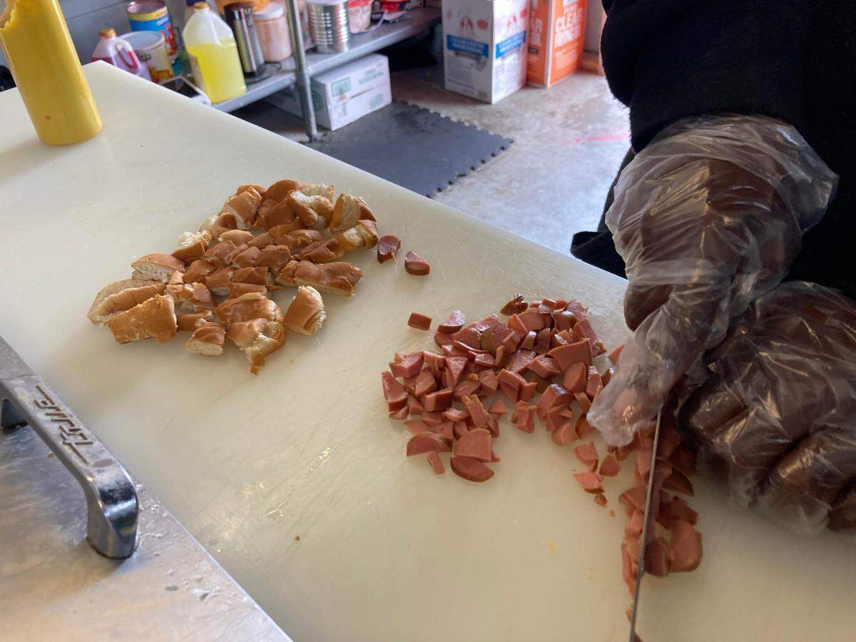 Tony Walker, owner of Doggie Dogs on Pio Nono Avenue in Macon, slices up a couple of hot dogs to make a scrambled dog. A scrambled dog is two hot dogs cut up and topped with chili, nacho cheese, barbecue chicken, shredded chicken and pickles.