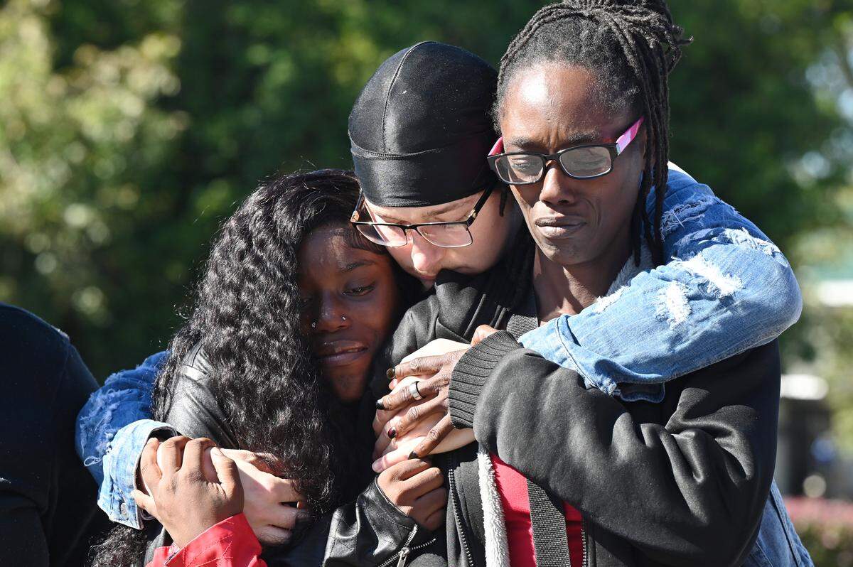 Family-friend Hunter Johnson (middle) hugs mom Demetria Dixon (right) and twin sister Contrella Dixon of Contrel Dixon during a balloon release in his honor on Friday, Oct. 31, 2025, outside of the Rosa Jackson Recreational Center in Macon, Georgia. Twenty-four-year-old Contrel Dixon died in hospice in late October after he was shot at his home in Macon on July 4.