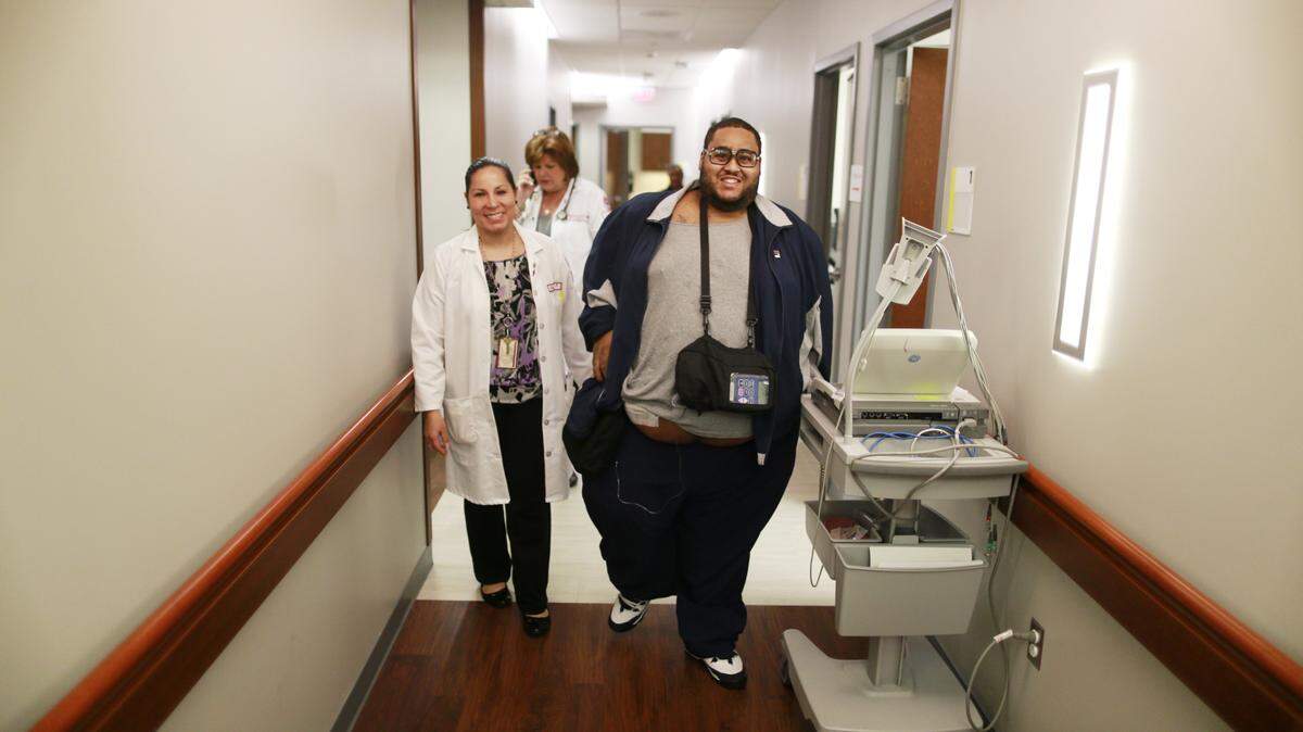 Dr. Eman Hamad walks with James Wagstaff-Duncan, right, who needed a heart transplant but at 480 pounds was not a candidate. Temple University doctors decided to implant a ventricular assist device.