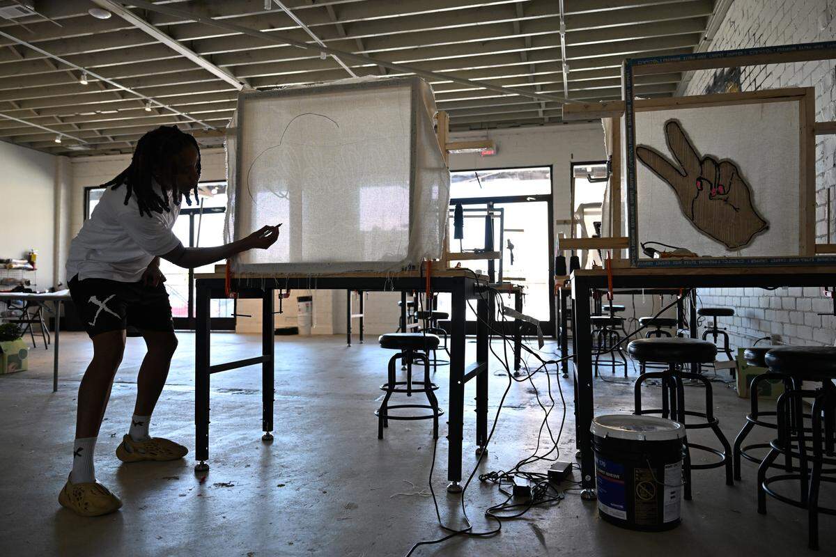 Wanna Tuft Studios owner Tonia Williams sketches a design displayed from a projector on a piece of mesh fabric before tufting on Wednesday, Sept. 3, 2025, in Macon, Georgia. Williams was inspired to start her own tufting studio after attending a similar class in Atlanta in early 2025. 