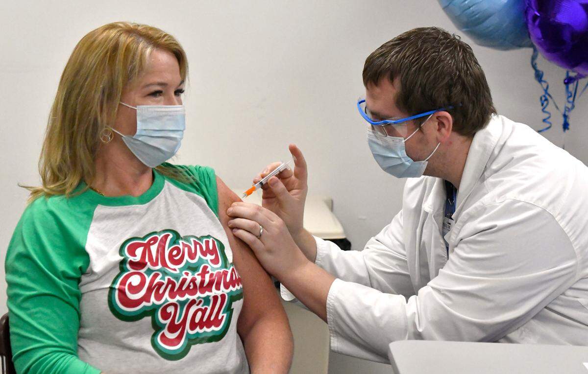 Laney Hogan, an RN in the ICU at Coliseum Medical Centers, receives the Moderna COVID-19 vaccine Thursday from fellow nurse Ben Kerscher.