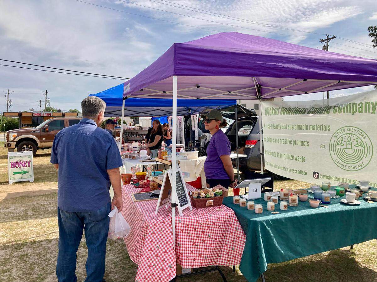 Jordan Reidy Celand, owner of Wicked Solutions Candle Company, right, talks with a visitor to the International City Farmers Market in Warner Robins.