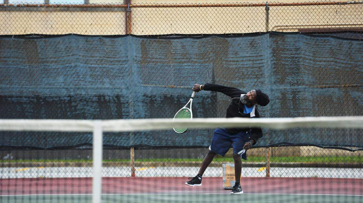 Edward Watson, 63, practices his tennis serve on mostly deserted courts behind the Lewis Recreation Center Monday.