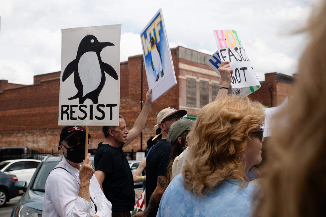 Gena Courtney and Craig Hamilton raise signs depicting penguins in protest of President Donald Trump’s most recent tariffs on April 5, 2025.