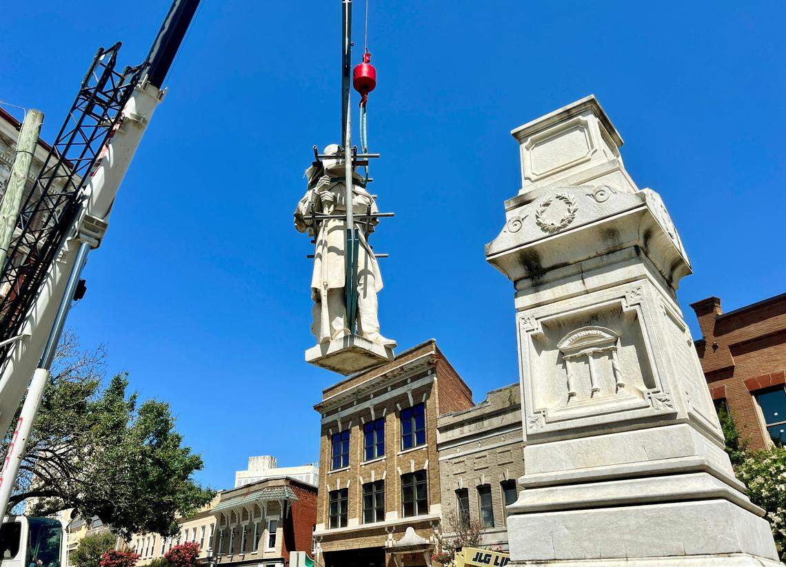 Crews lower the Confederate monument on Cotton Avenue while removing it Wednesday morning. The monument will be relocated to Whittle Park in from of Rose Hill Cemetery.