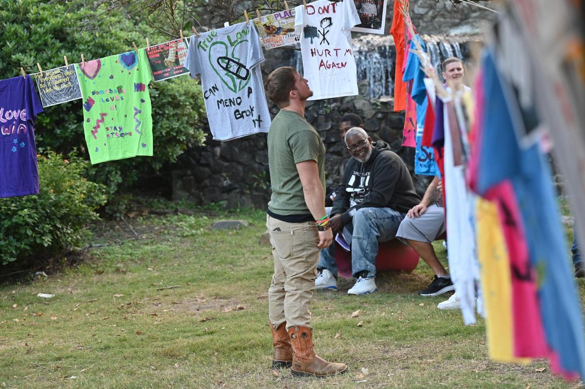 Addison Einhorn looks at t-shirts on a clothesline as a part of the Rescue Mission Georgia clothesline project during the Domestic Violence Awareness Month candlelight vigil on Tuesday, Oct. 29, 2024, in Macon, Georgia. The vigil presented by Rescue Mission of Middle Georgia and Crisis Line and Safe House of Central Georgia honored victims of domestic abuse at the end of October, which is National Domestic Violence Awareness Month.