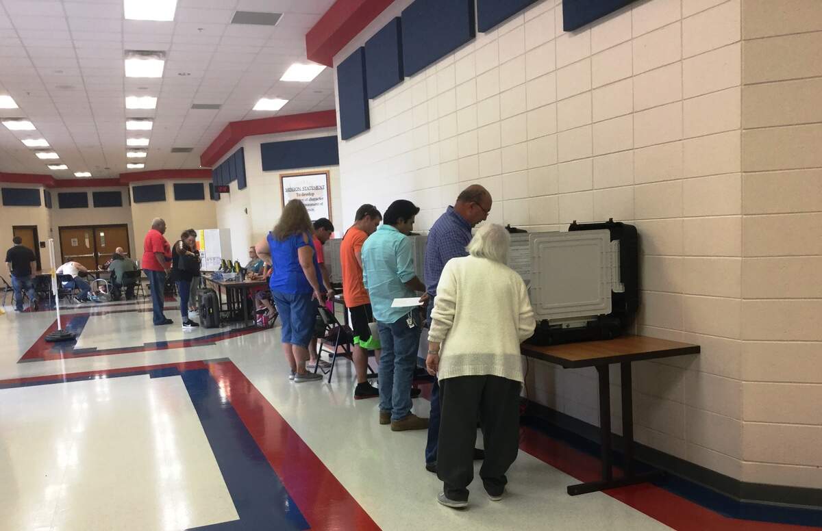 Carolyn Childs, a poll worker, helps a voter Tuesday at the Veterans High School voting precinct in Houston County.