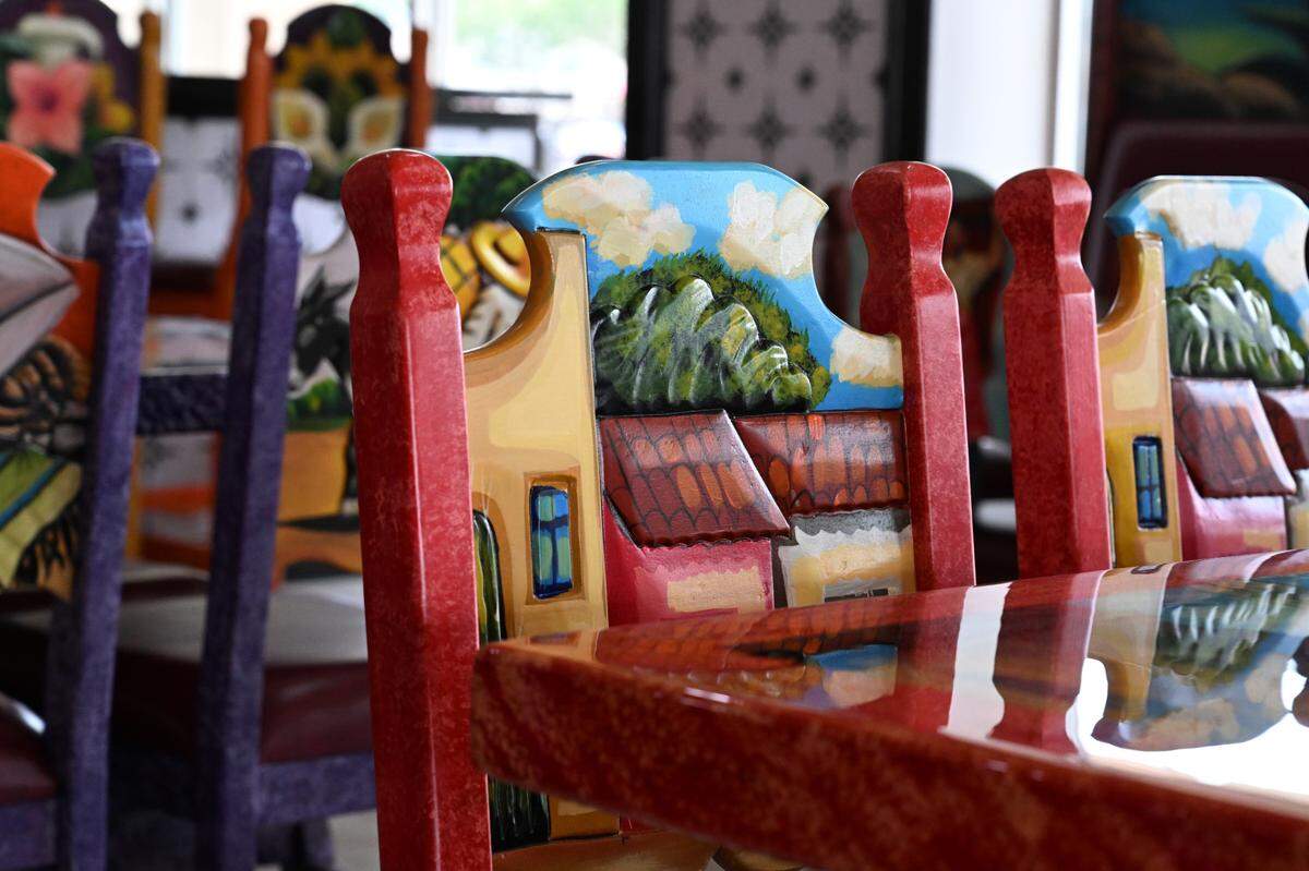 Hand carved and painted wooden chairs sit inside of El Metate Mexican Restaurant from Cumex Decoration LLC.