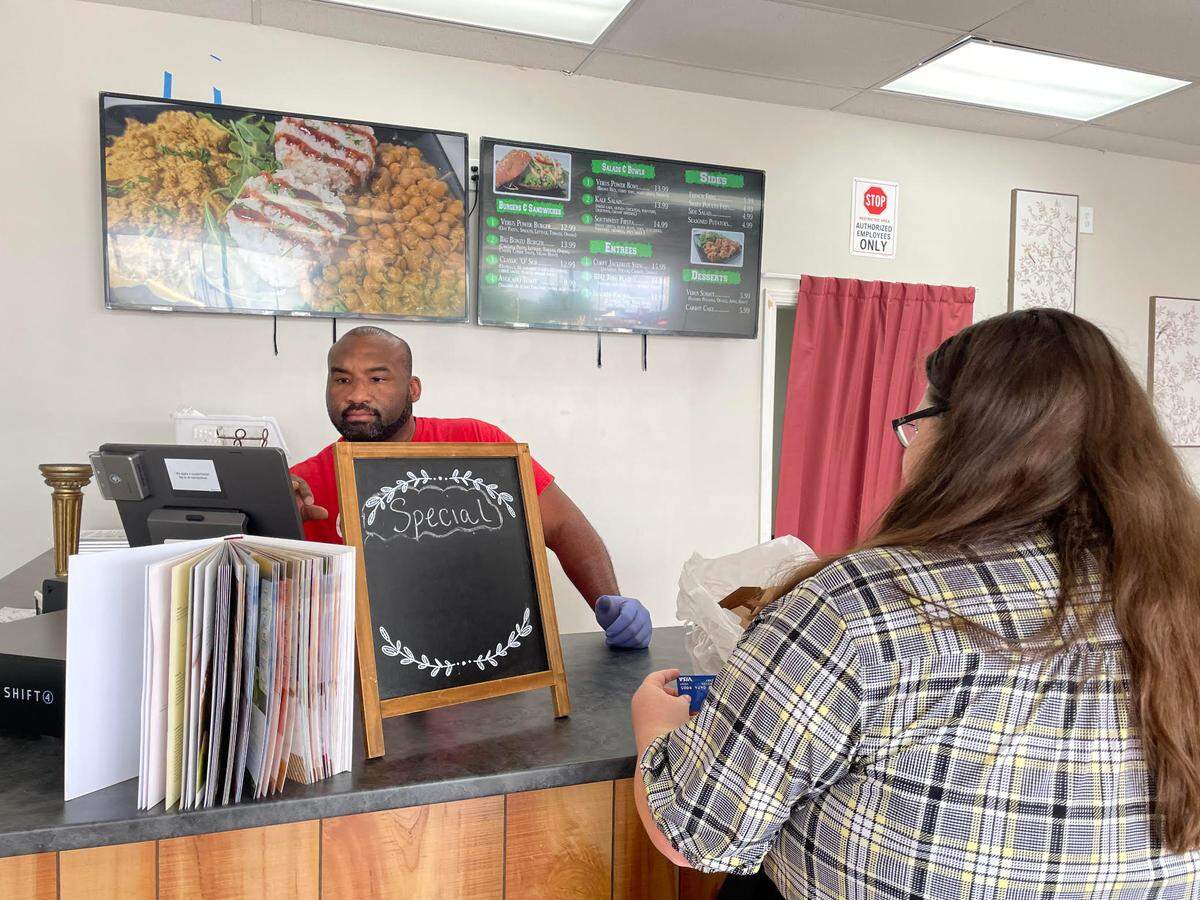 Mary Jo McCary, a tourism specialist for the Byron Convention & Visitors Bureau, pays for a to go order at Verus Vine Plant Based Kitchen at 100 Hamilton Pointe, Suite 145, in Byron. Tory Thomas, the restaurant’s co-owner, is at the cash register.