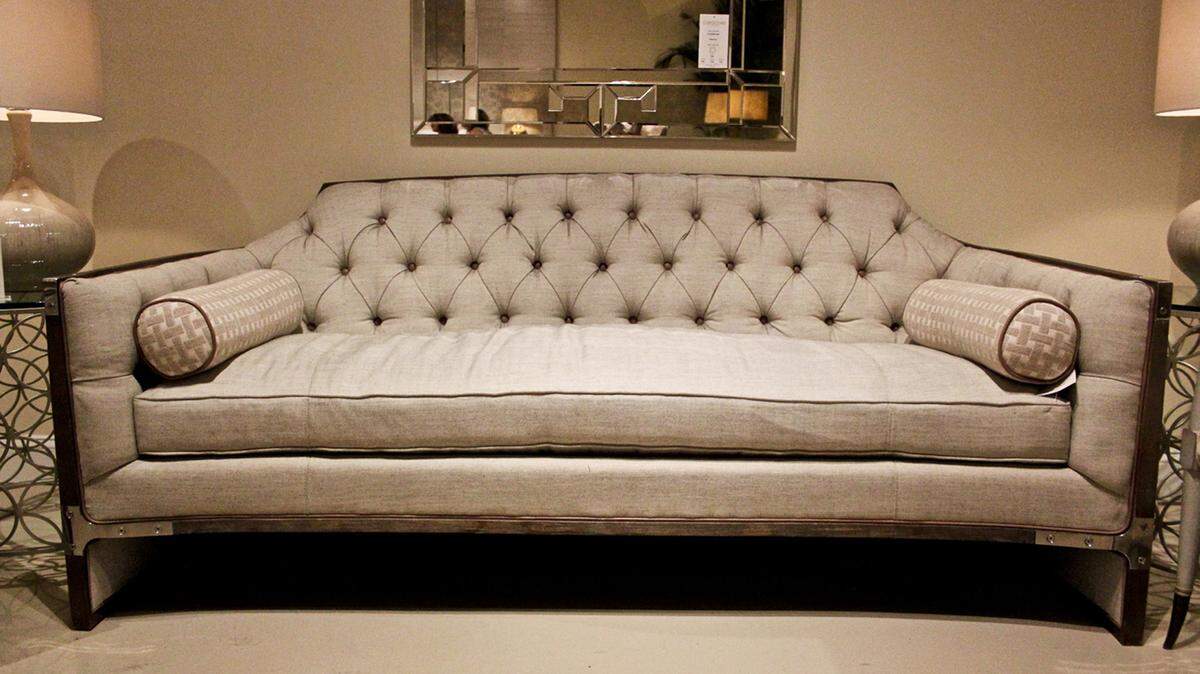 Caracole's tufted back sofa with contrasting leather buttons and wood frame accented with steel. 