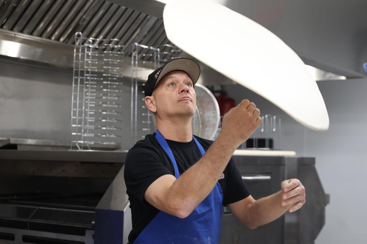 Amici kitchen manager Branden Hudson tosses pizza dough while making a Pineapple Express pizza during staff training on Wednesday, Oct. 16, 2024, in Perry, Georgia. The new Perry location of Amici is set to open to the public on Monday and will be Perry’s first brewery.