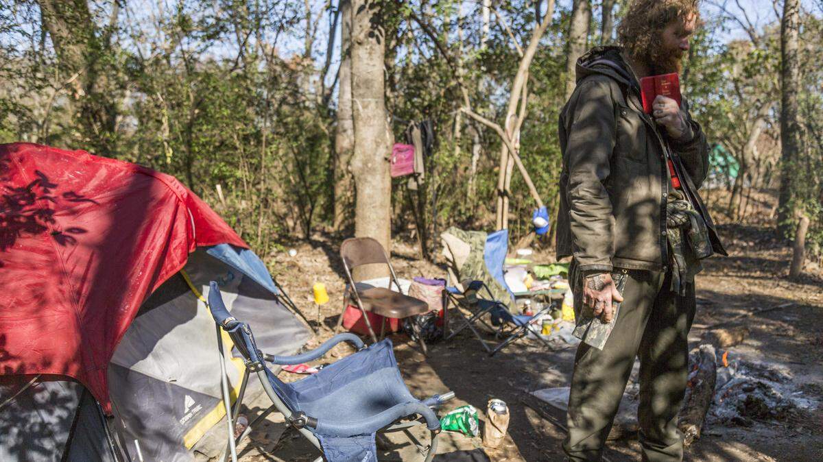 Billy Mitchell holds onto a copy of the New Testament he pulled from a pocket in his coat at his campsite by the Ocmulgee River in Macon. Mitchell and others camping inside Macon’s Central City Park must leave by Monday.