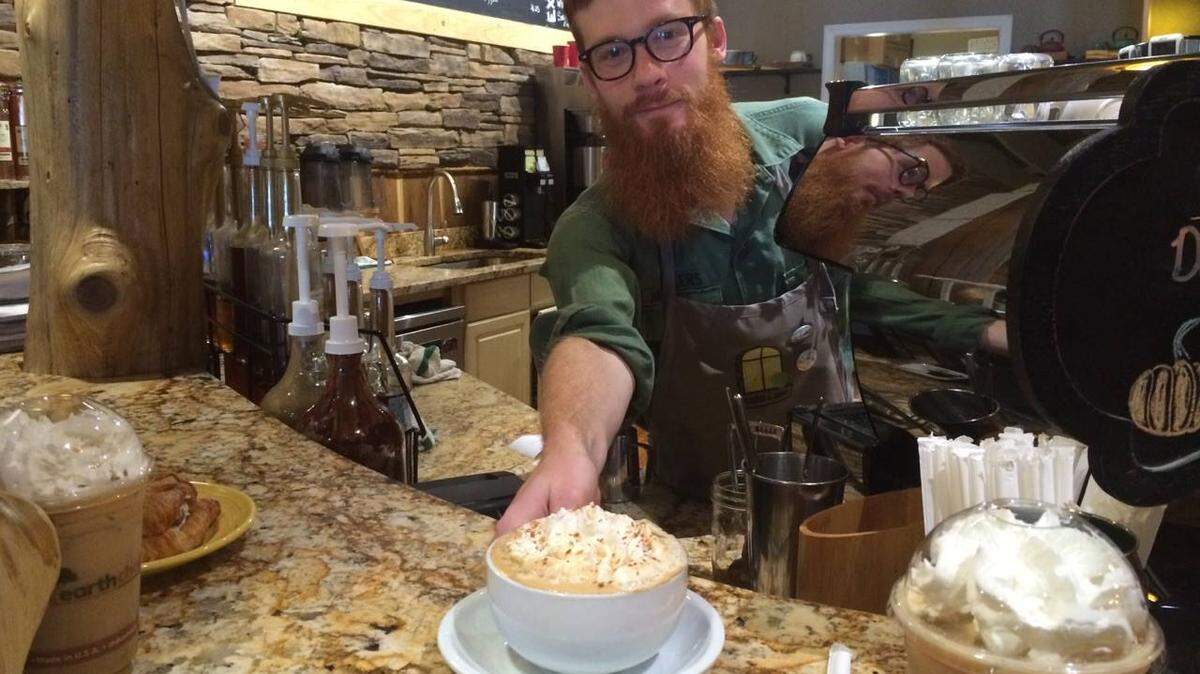 A Taste & See Coffee Shop employee serves a hot cup of cappuccino. The coffee shop celebrated ten years in business in 2023.