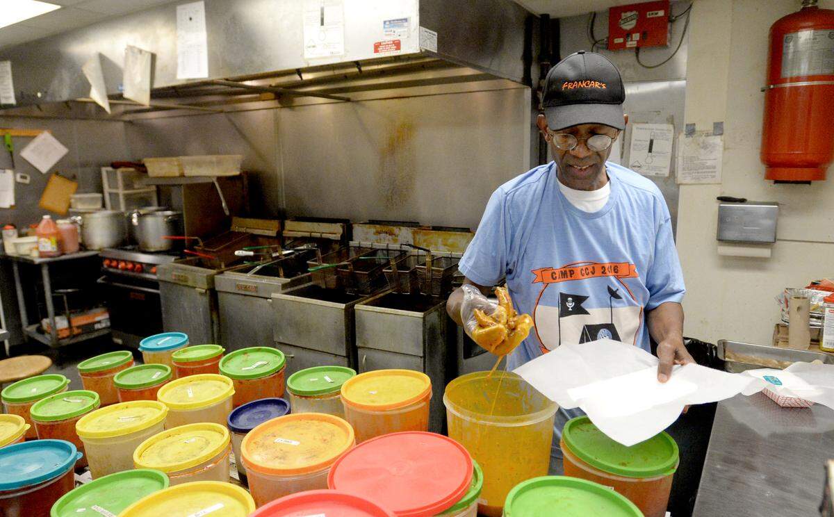 Carl Fambro dips wings in Mercer Gold at Francar’s Buffalo Wings.