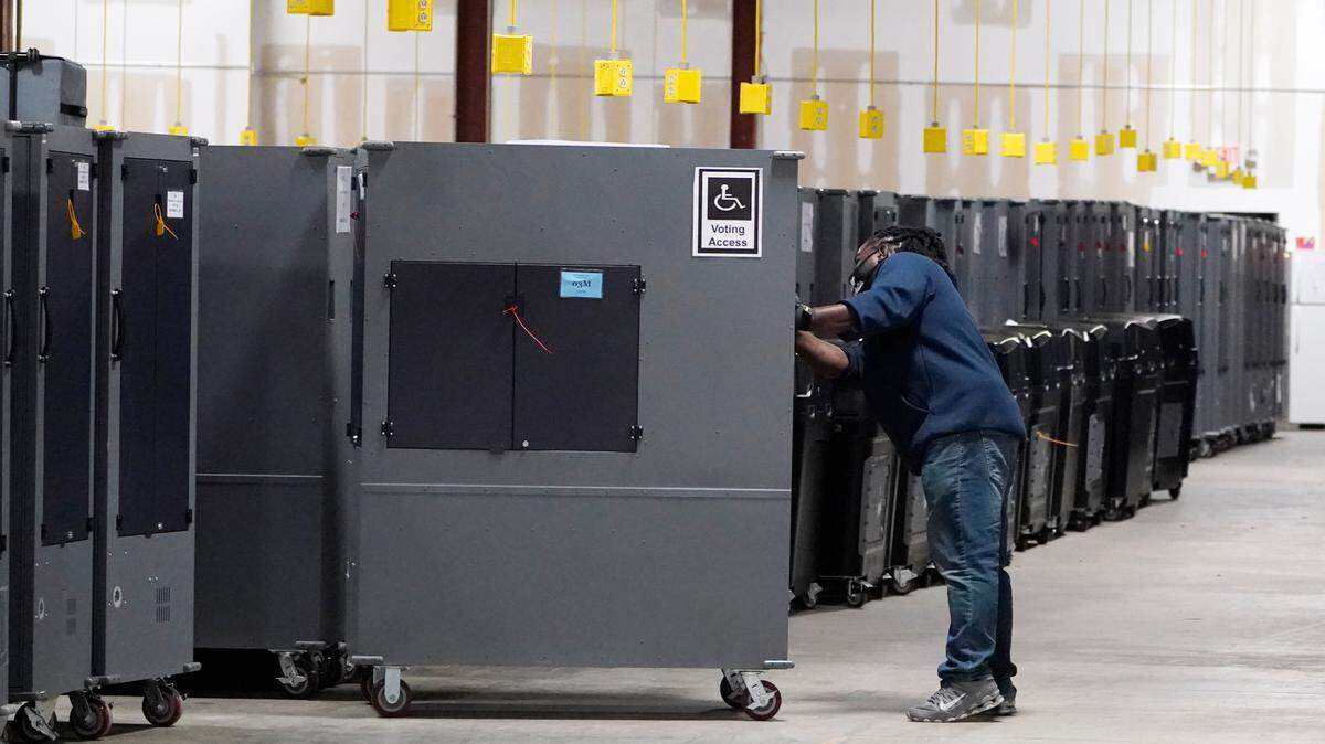 A worker returns voting machines to storage at the Fulton County Election preparation Center on Nov. 4, 2020, in Atlanta, Ga. The list of security breaches at local election offices since the 2020 election keeps growing, with investigations ongoing in at least three states, Colorado, Georgia and Michigan. Security experts say the breaches by themselves have not necessarily increased threats to the November elections, but say they increase the possibility that rogue election workers could access election equipment to launch attacks. (AP Photo/John Bazemore, File)