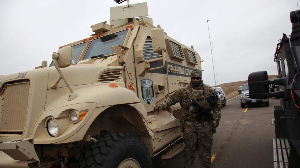 A member of the Stutsman County, N.D., SWAT team who declined to give his name nor to be identifiable by badge stands guard by an armored personnel carrier equipped with an LRAD, or long range acoustic device, while deployed to watch protesters demonstrating against the Dakota Access Pipeline encroaching the water source near the Stand Rock Sioux Reservation, in Cannon Ball, N.D., in this 2016 file photo.