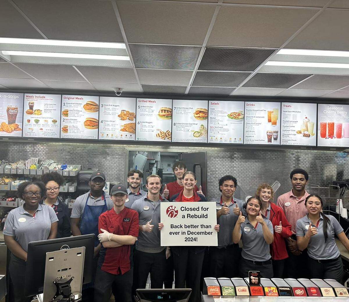 Team members of the Zebulon Road Chick-fil-A location hold a sign prior the closure of the restaurant for remodeling. The restaurant was set to reopen in December but is now ahead of schedule.