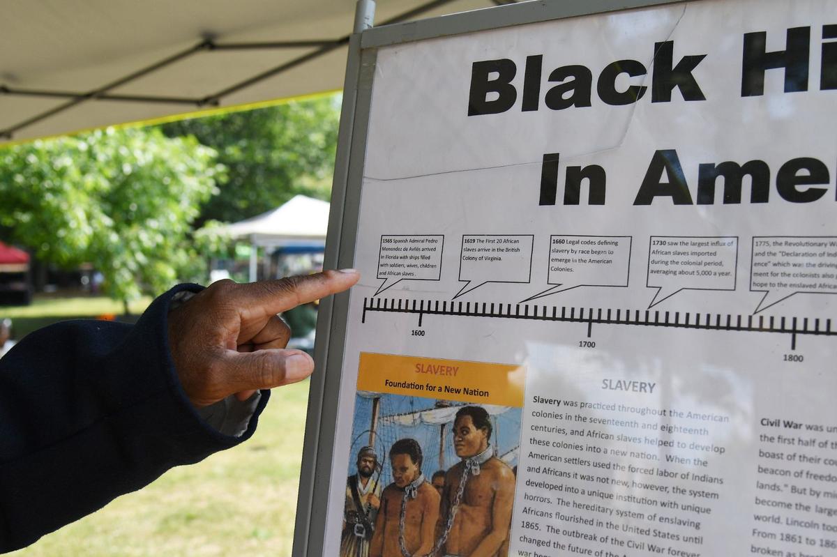 Lonnie Davis points at a “Black History in America” timeline at this tent at the 32nd Juneteenth Freedom Festival on Saturday, June 15, 2024, at Tattnall Square Park in Macon, Georgia. Davis does living history presentation on the Georgia African Brigade, three Black Union regiments that organized in Macon during the Civil War.