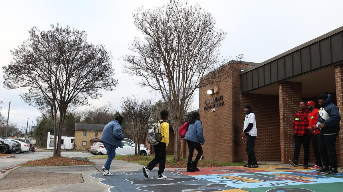 Members of the Macon Rampage (right) greet students as they walk into L.H. Williams Elementary School on Thursday, Feb. 20, 2025, in Macon, Georgia. The Macon Rampage, Macon’s semi-professional football team, welcomed students to school on the first day back from February break as a a part of the United Way’s Walking School Bus initiative to encourage student attendance.